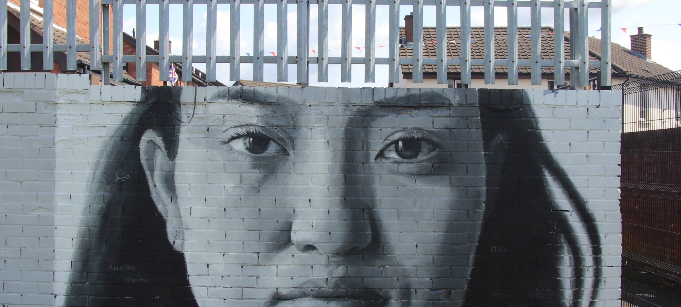 ‘We Are Here’, een muurschildering op de notoire &#039;Peace Wall&#039; in Belfast, door iMAE-alumnus Leyli Rashidirauf. De Peace Wall loopt dwars langs de Shankill Mission, een belanrgijke thuisbasis voor artisteducator-studenten bij ArtEZ. Foto door Brian Kelly