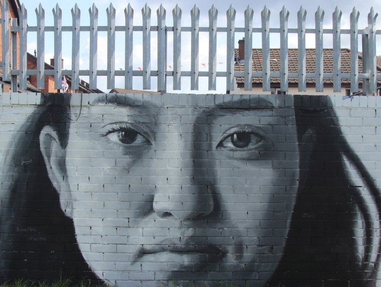 ‘We Are Here’, a mural on the 'Peace Wall' in Belfast, by iMAE-alumnus Leyli Rashidirauf and people of the local community. The preace wall runs along the Shankill Mission. Photo by Brian Kelly