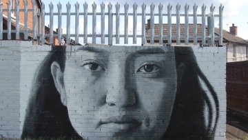 ‘We Are Here’, a mural on the 'Peace Wall' in Belfast, by iMAE-alumnus Leyli Rashidirauf and people of the local community. The preace wall runs along the Shankill Mission. Photo by Brian Kelly